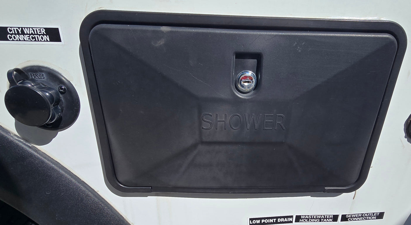 RV rental showing city water, outdoor shower, and utility access points on its exterior.