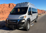 Silver Ram RV rental on a desert road with red rock mountains under a blue sky, ready for adventure and scenic travel.