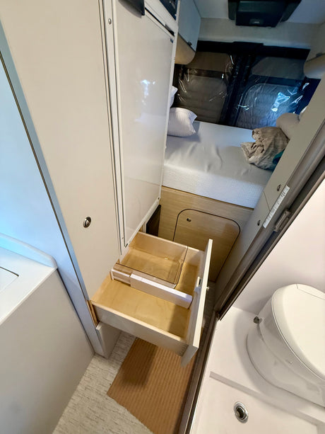 Inside an RV rental: pull-out drawer storage, comfortable bed, and compact bathroom for convenient travel.