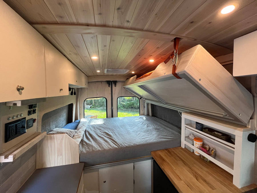 RV rental: Cozy camper van interior with lift bed, wooden ceiling, and kitchen counter for comfortable travel.