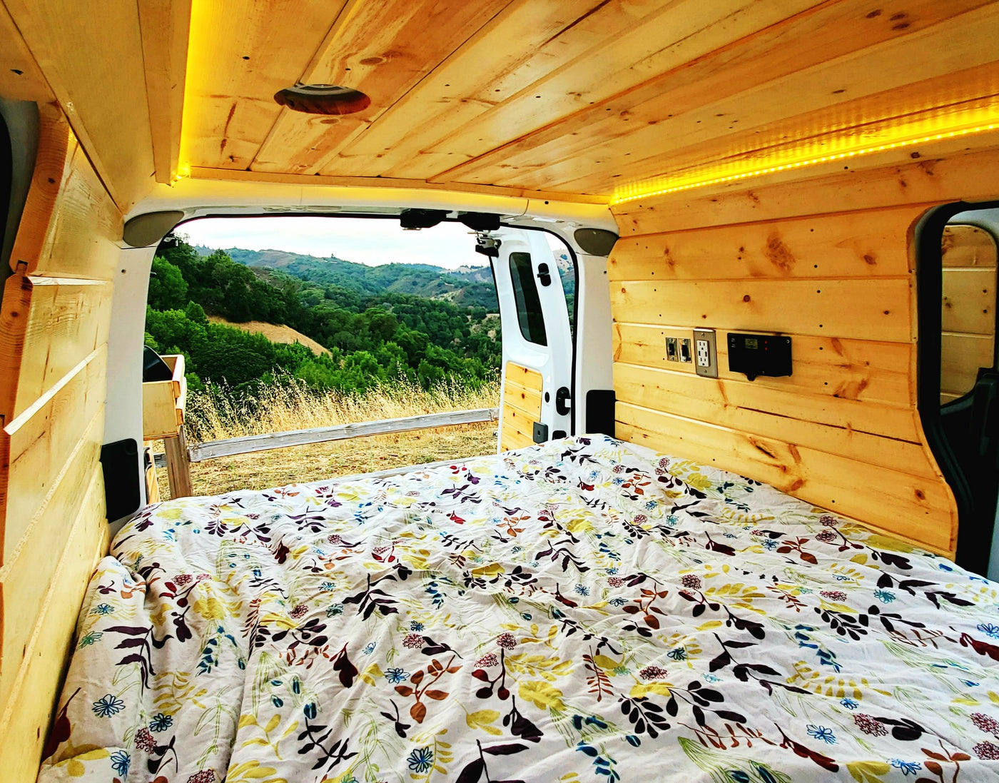 Step into this cozy RV rental's wooden interior, offering a comfy bed and scenic nature views from the open back. — photo 4