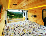 Step into this cozy RV rental's wooden interior, offering a comfy bed and scenic nature views from the open back.