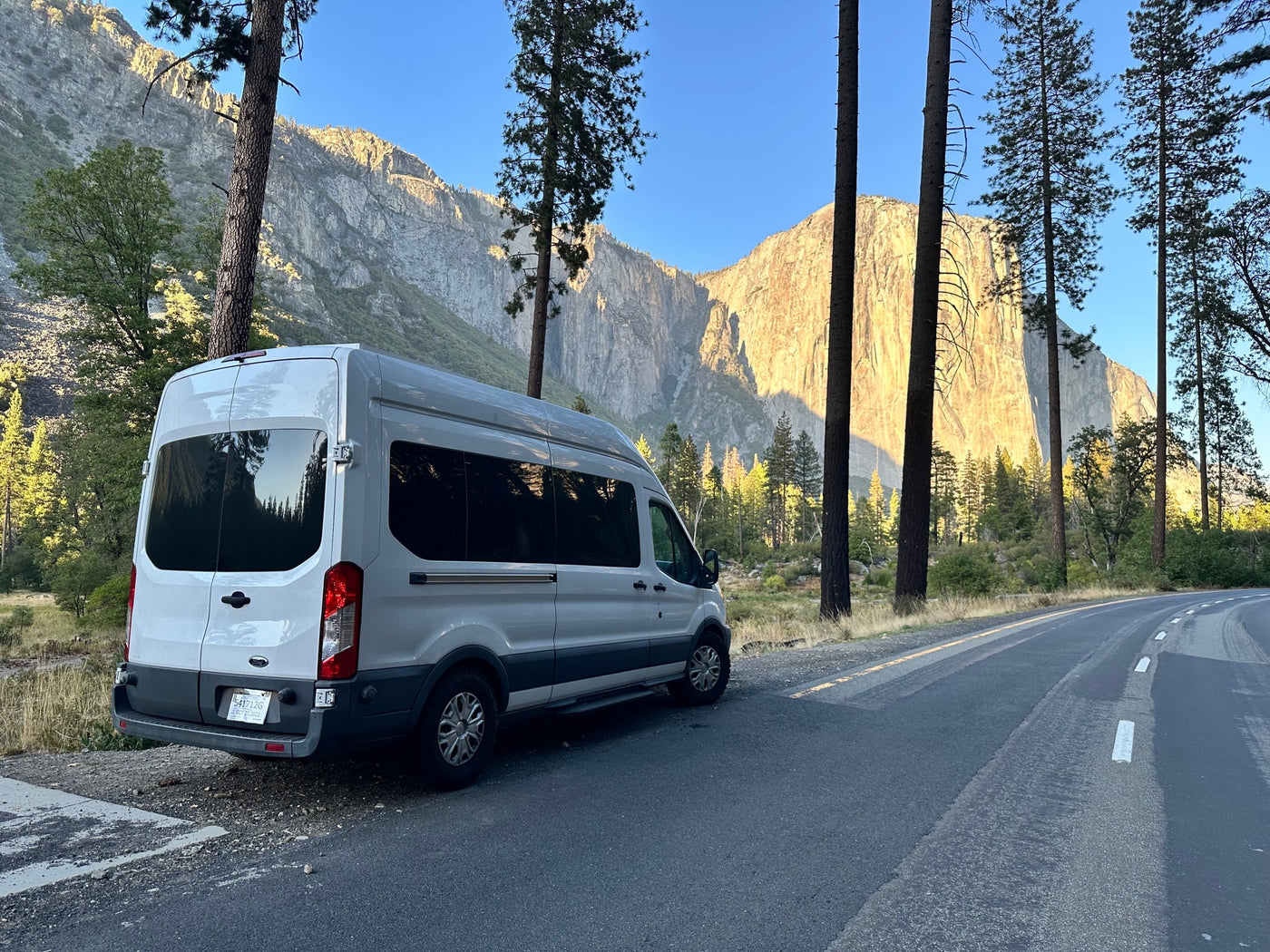  framed by mountains and pine trees.|White RV rental van parked on a roadside — photo 12