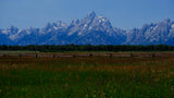 Explore the stunning Grand Teton mountains, green meadows, and wooden fence. Perfect scenery for your RV rental journey.