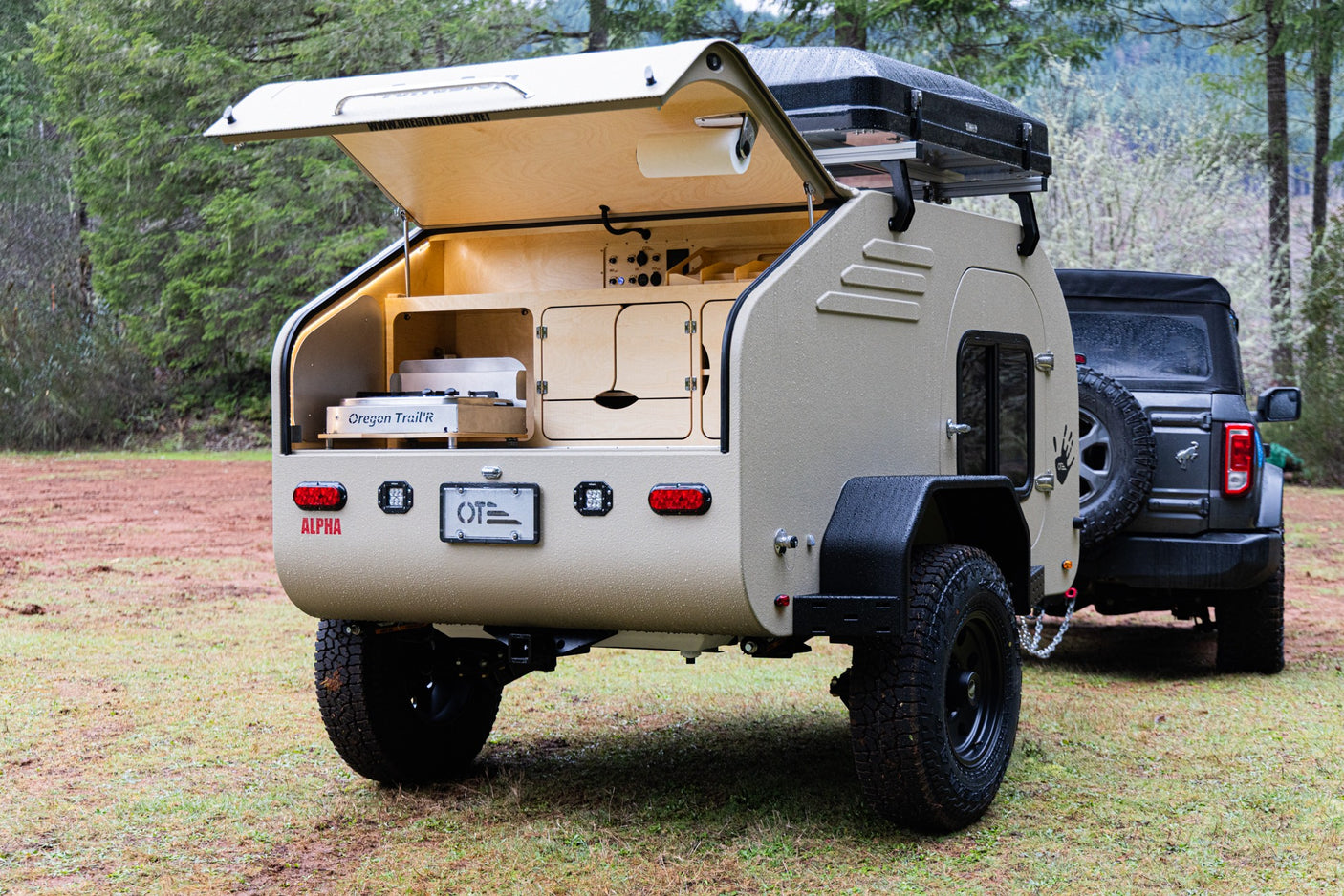 Teardrop RV rental: off-road camper with open outdoor kitchen & rooftop tent, ready for adventures in nature with an SUV.