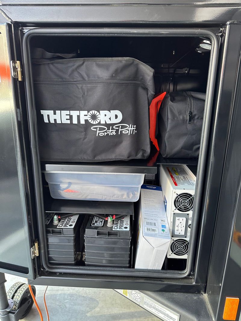 Organized RV rental storage: a Thetford Porta Potti, robust batteries, and a power inverter for your journey. — photo 5