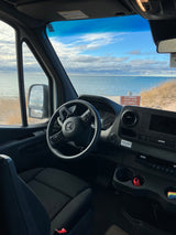 RV rental van offers stunning beach views. Mercedes-Benz Sprinter interior with clear dashboard visibility.