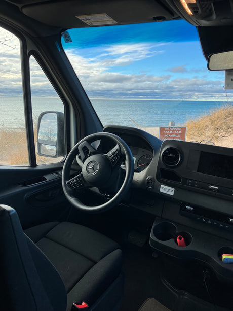 RV rental van offers stunning beach views. Mercedes-Benz Sprinter interior with clear dashboard visibility.