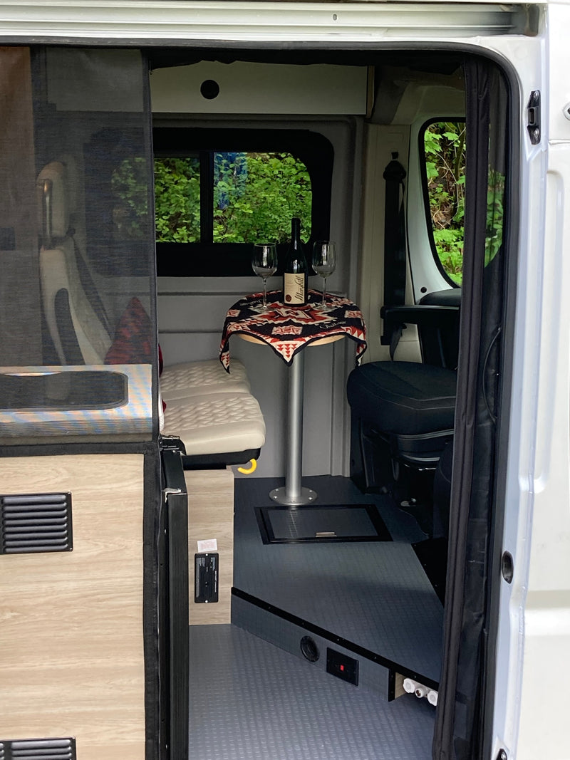  parked in a lush green forest. Interior visible.|Open side door of white Winnebago pop-top RV rental — photo 13