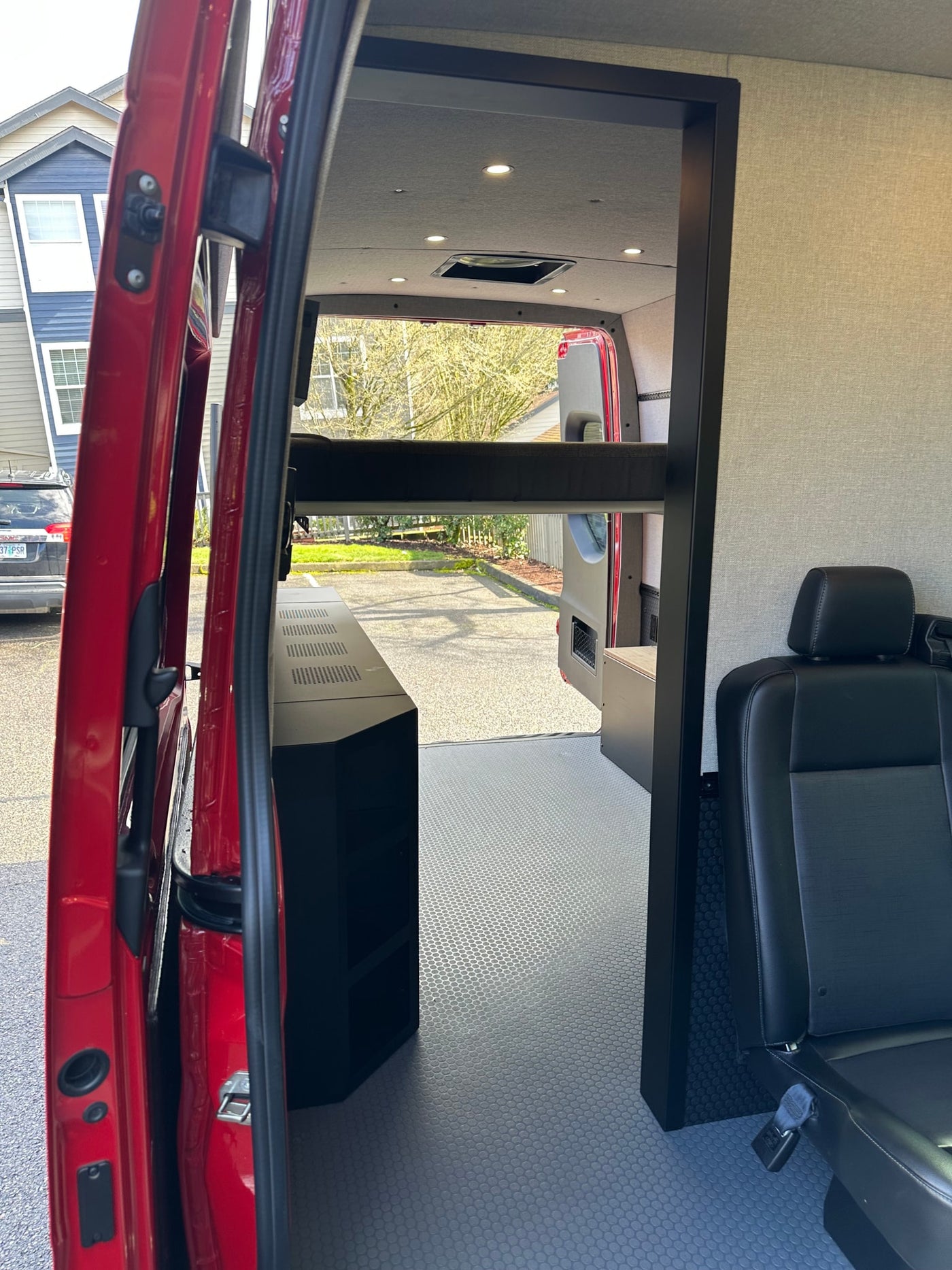 Interior view of a red van conversion with a bunk bed, counter, and swiveling seat, ideal for an RV rental. — photo 7