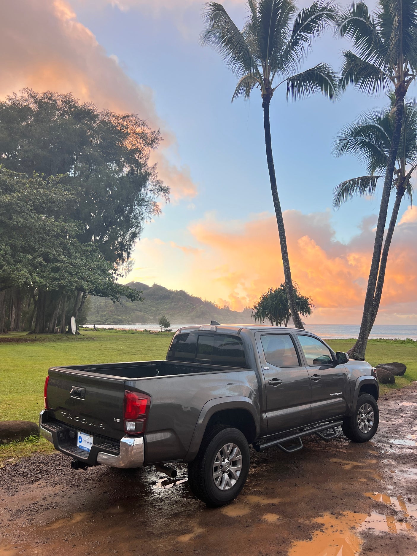 Gray Toyota Tacoma pickup on a muddy path at a tropical beach during sunset. An ideal setting for an RV rental adventure.