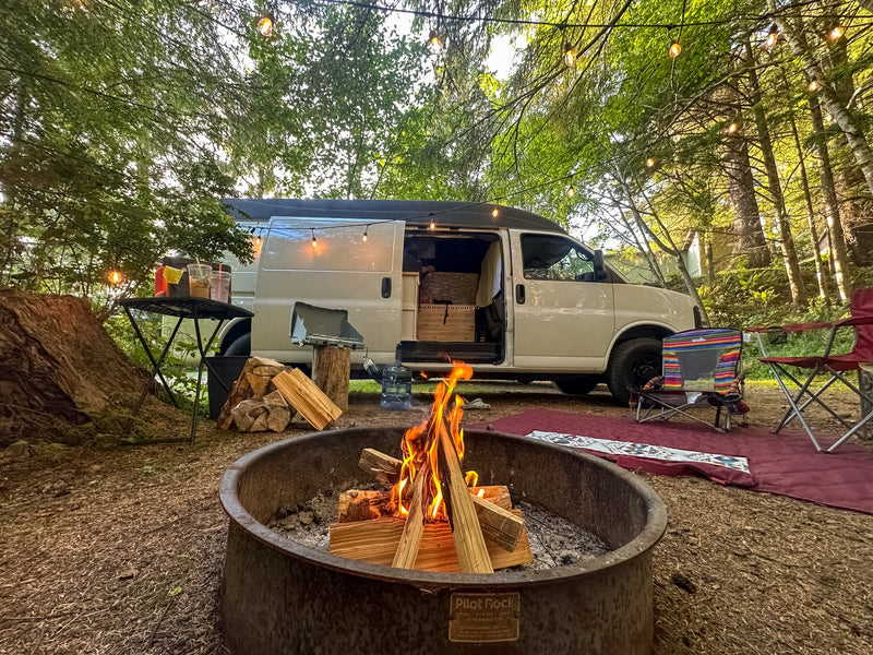 Cozy camping setup with a roaring campfire and string lights next to an RV rental van in the woods. Perfect outdoor adventure.|Cozy RV rental interior with wood details — photo 1