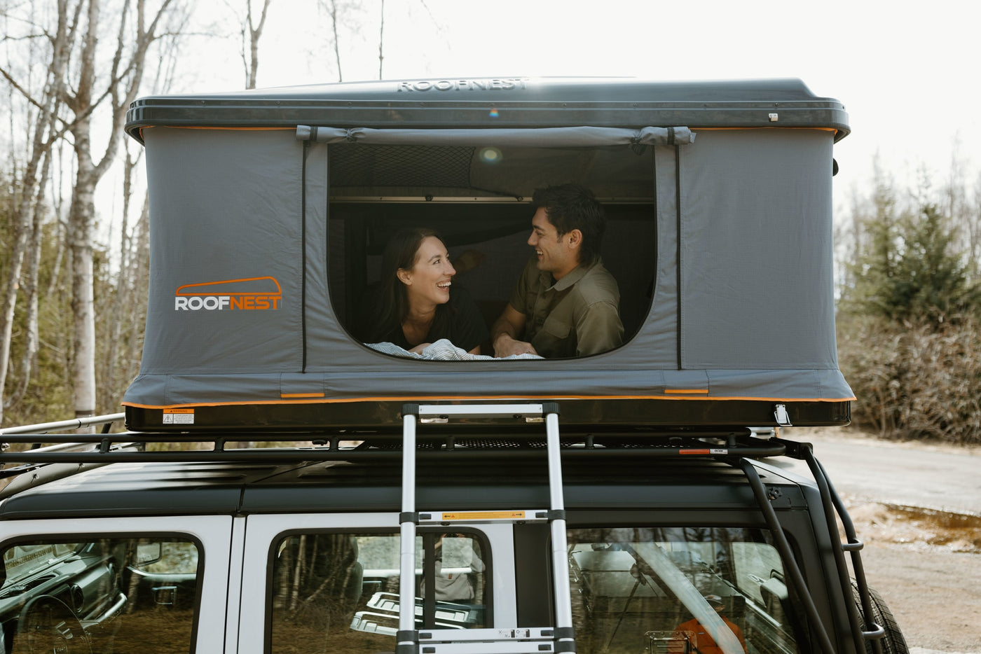 Happy couple in a Roofnest roof-top tent on a white SUV, a unique RV rental option for camping adventures. — photo 9