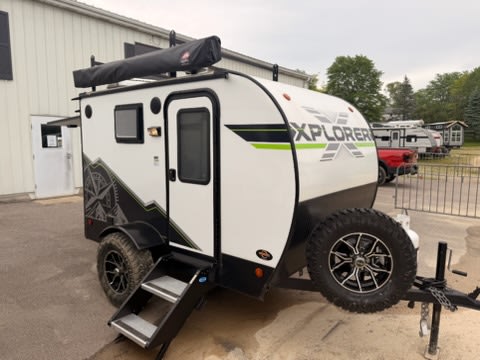 Compact Xplorer off-road rv rental: a white teardrop travel trailer with large all-terrain tires and roof awning.|This compact RV rental features a full outdoor kitchen — photo 1