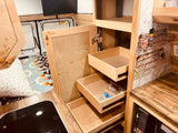 Organized RV rental interior featuring custom wood storage, pull-out drawers, compact kitchen area, and sleeping space.