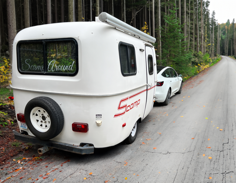 White Scamp travel trailer, ideal for RV rental, with a Tesla parked on a scenic forest road. "Scamp Around" on RV window. — photo 4