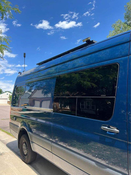 Blue RV rental van, ready for adventures! Features custom tinted windows and roof-mounted antenna/solar setup.