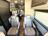 RV rental interior: luxurious quilted captain's chairs, a functional kitchen, and comfortable rear seating visible.