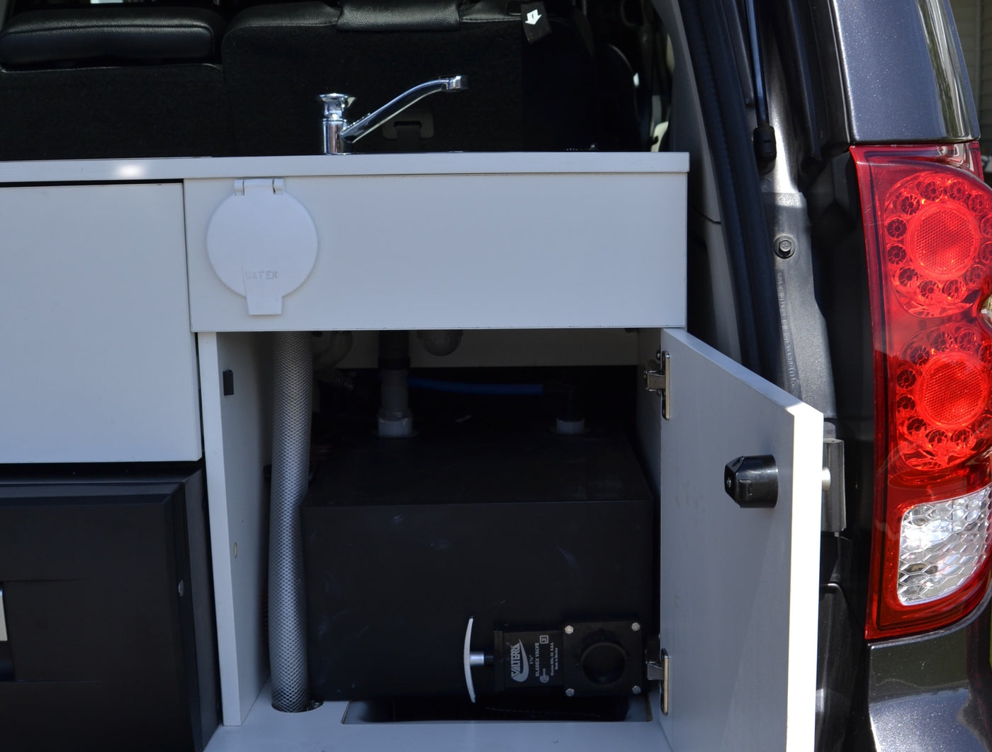  and Dometic fridge.|Pop-top minivan camper with open sliding door reveals a cozy bed — photo 13