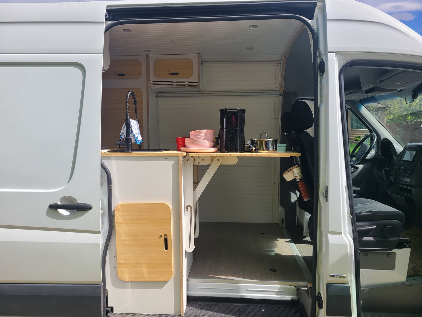 Spacious van conversion interior: custom kitchen with sink & fold-down table. Perfect RV rental for road trips.