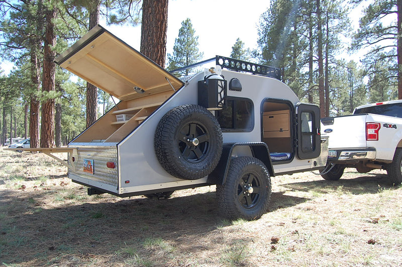 Teardrop RV rental with open galley parked in a pine forest. Great for camping and outdoor adventures with a truck. — photo 1