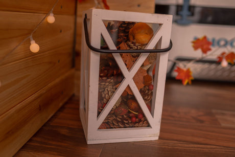 Autumn decor inside an RV rental, featuring a lantern with pinecones, leaves, and cozy string lights.