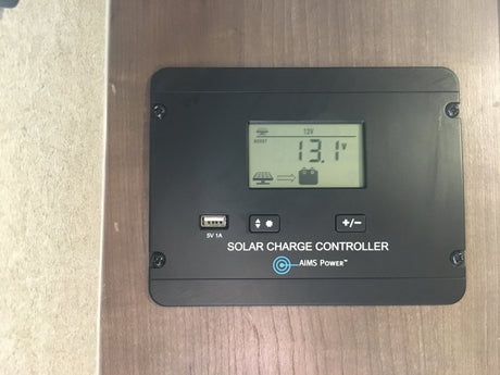 AIMS Power solar charge controller in an RV rental, displaying 13.1V battery voltage & 12V system. USB output for charging.