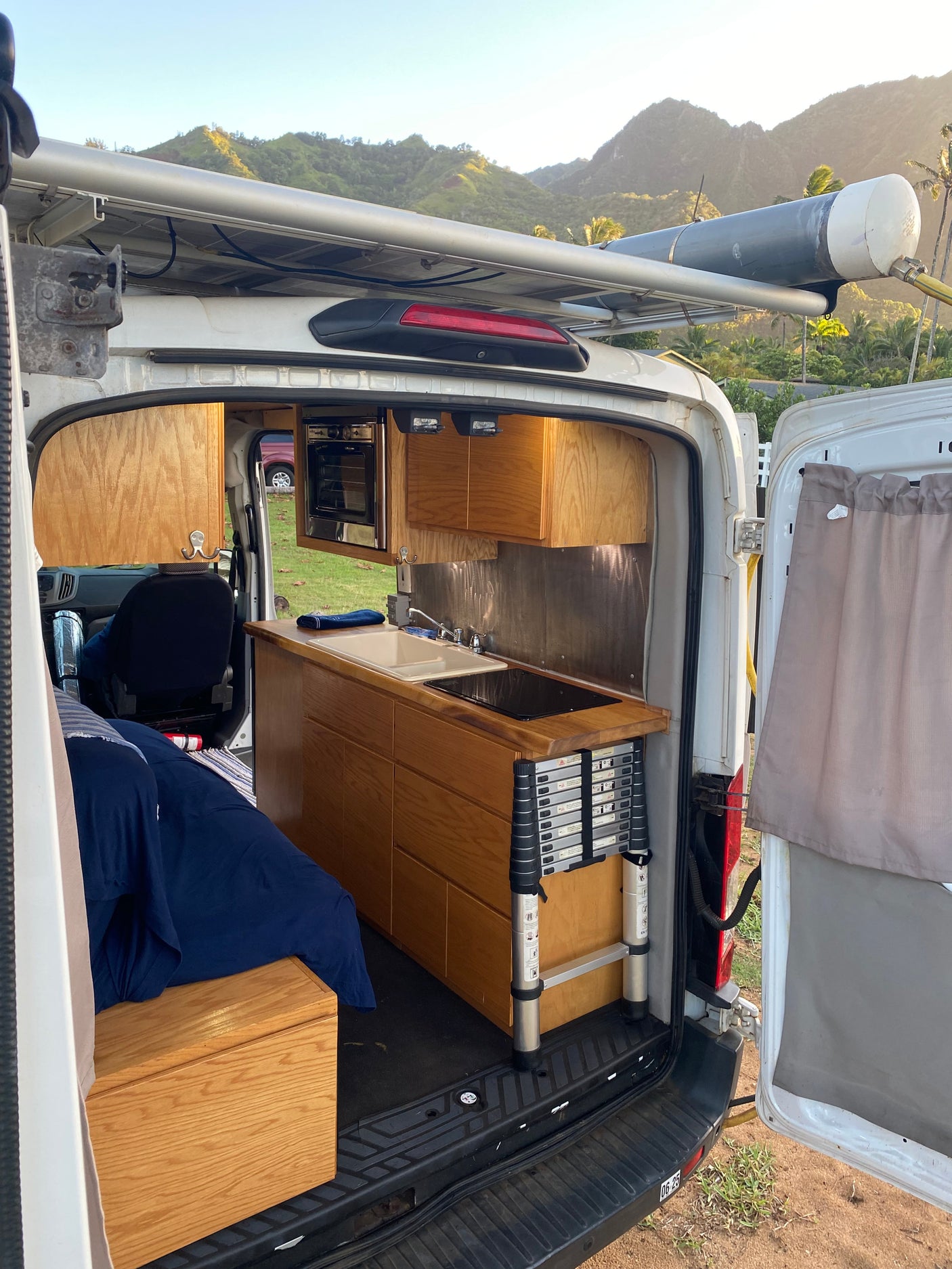 Explore in this RV rental camper van! Full kitchen, bed, roof water tank, and stunning mountain views.