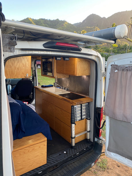 Explore in this RV rental camper van! Full kitchen, bed, roof water tank, and stunning mountain views.