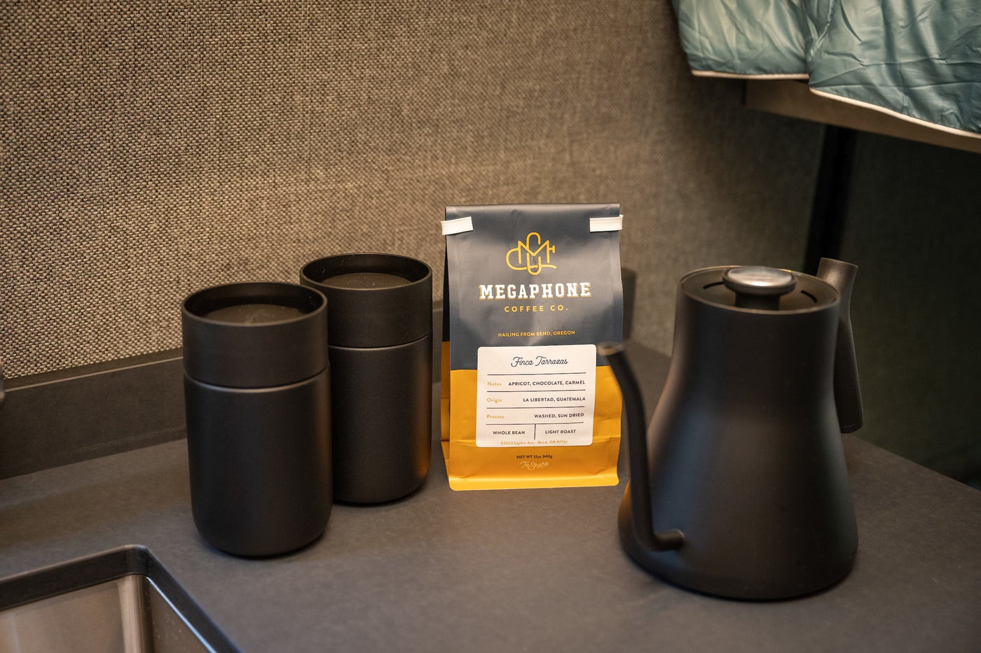 Compact coffee station in an RV rental, featuring Megaphone Coffee beans, a kettle, and two black tumblers. — photo 11