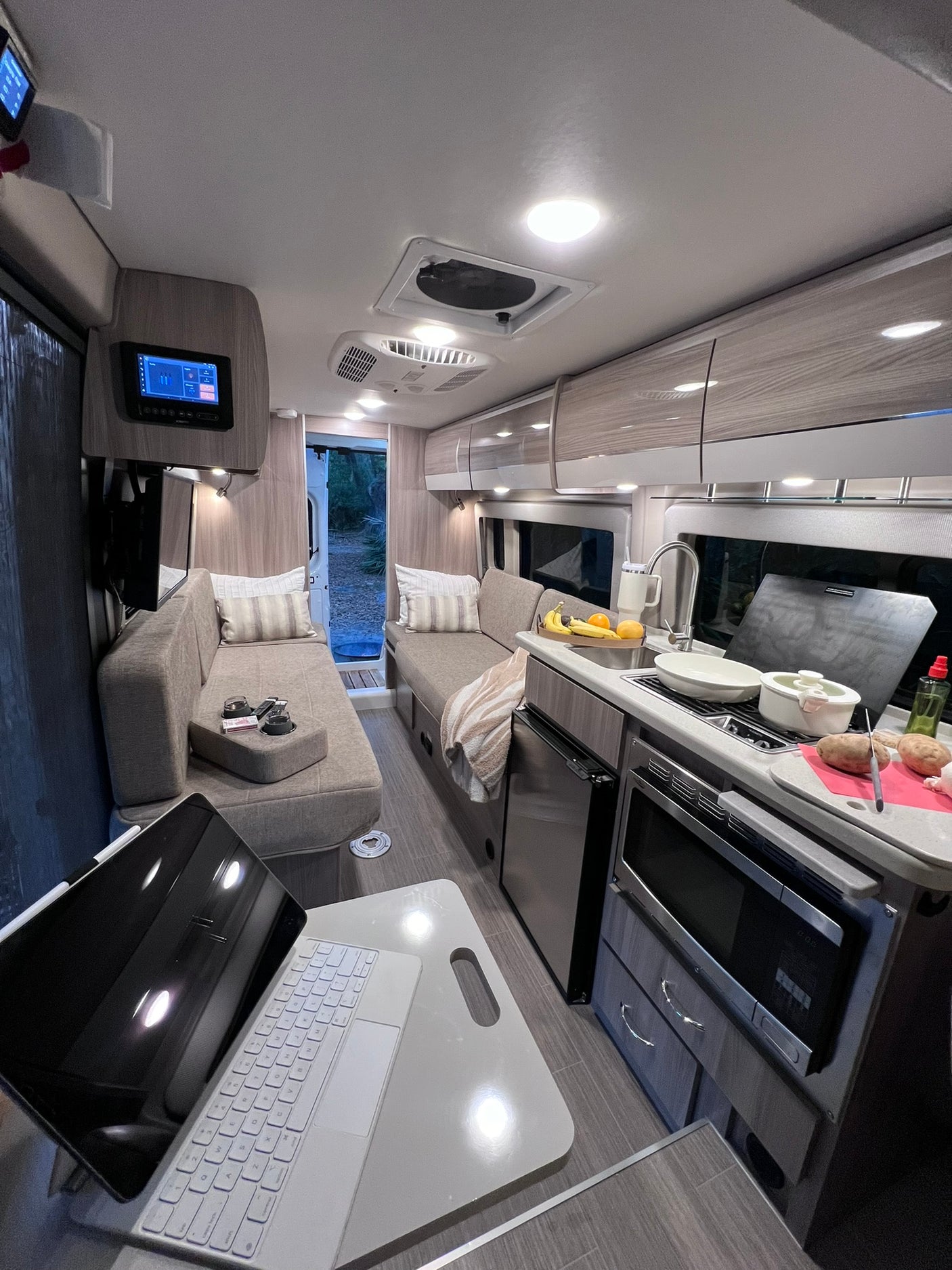 Inside a modern **rv rental**: kitchen prep in a compact, well-lit camper van with cozy seating.