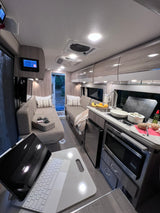 Inside a modern **rv rental**: kitchen prep in a compact, well-lit camper van with cozy seating.