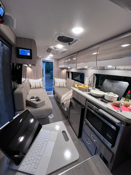 Inside a modern **rv rental**: kitchen prep in a compact, well-lit camper van with cozy seating.
