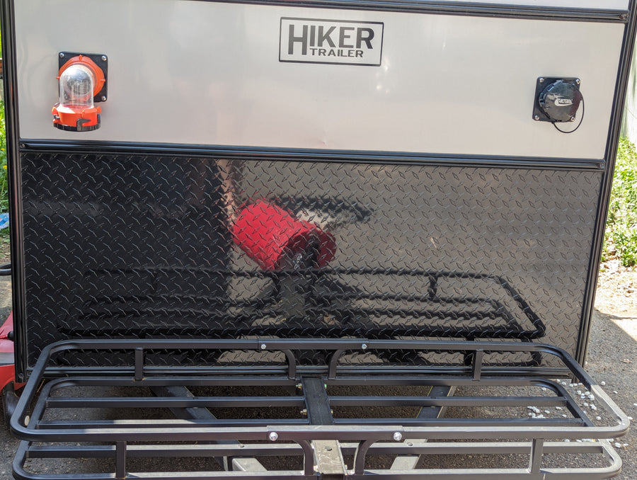 Back of a Hiker Trailer RV rental, featuring utility hookups, durable diamond plate, and a rear cargo rack.