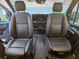 Spacious RV rental van front cabin, featuring two black seats, dashboard, and the road ahead through the windshield.