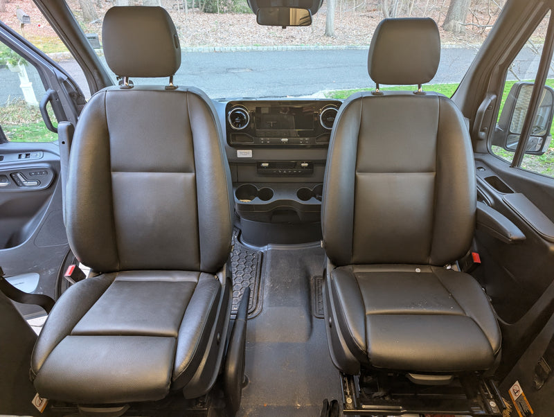 Spacious RV rental van front cabin, featuring two black seats, dashboard, and the road ahead through the windshield. — photo 13