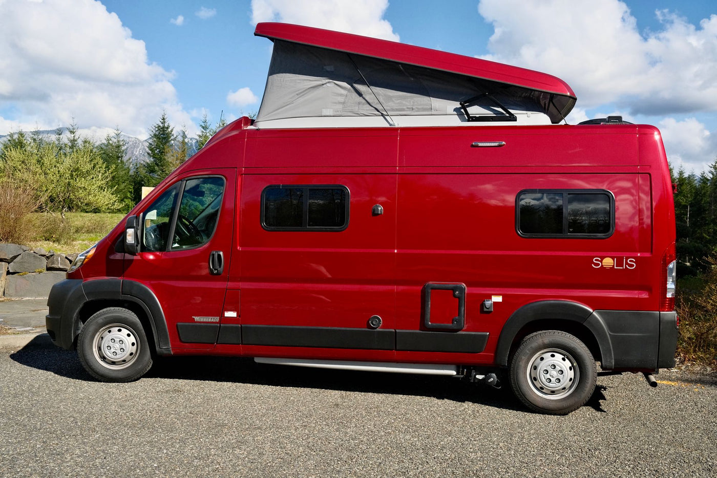  parked in a scenic mountain setting.|Explore in a red Winnebago Solis pop-top RV rental — photo 2