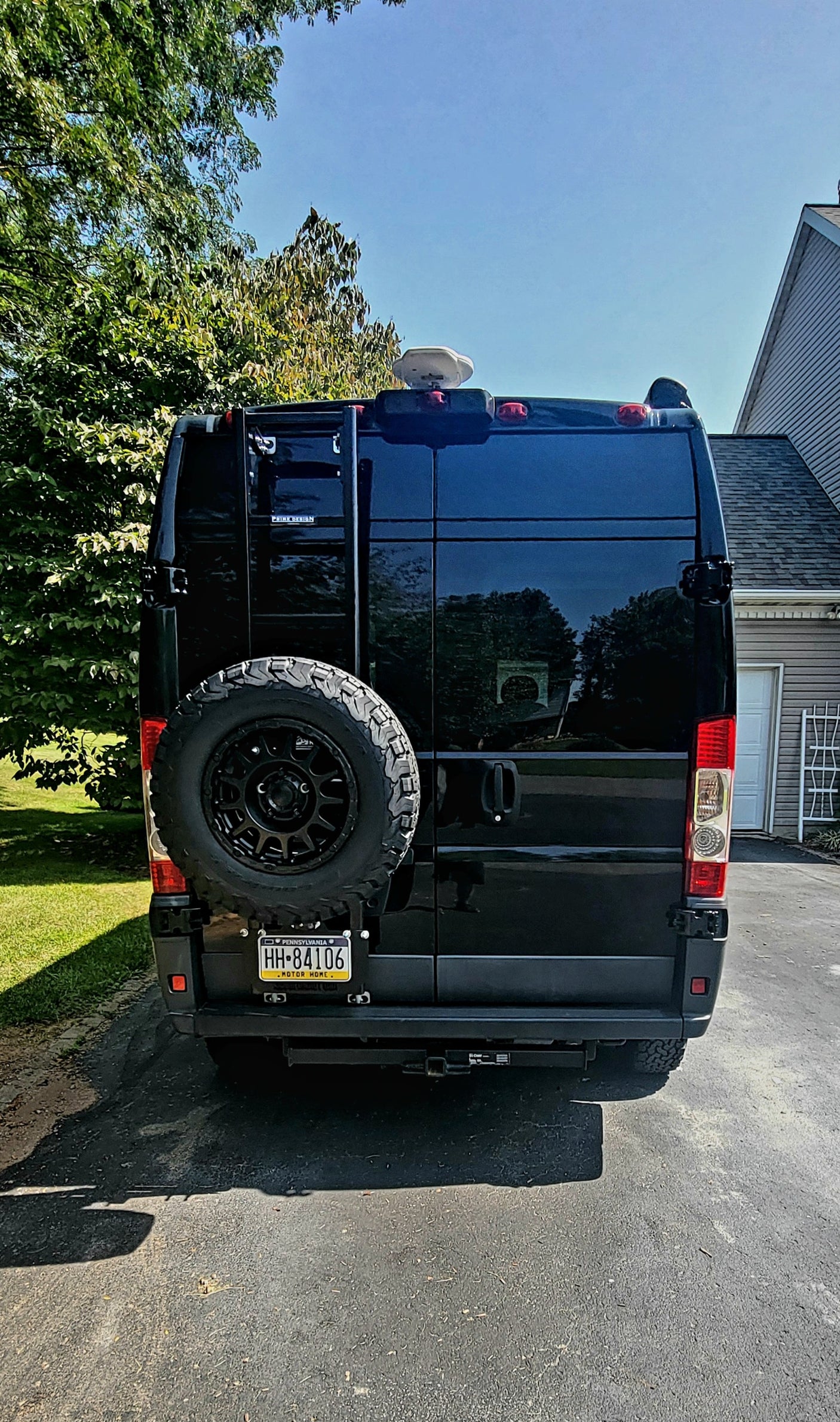 Rear of a black RV camper van, perfect for RV rental. Shows spare tire, ladder, and PA 'MOTOR HOME' license plate.