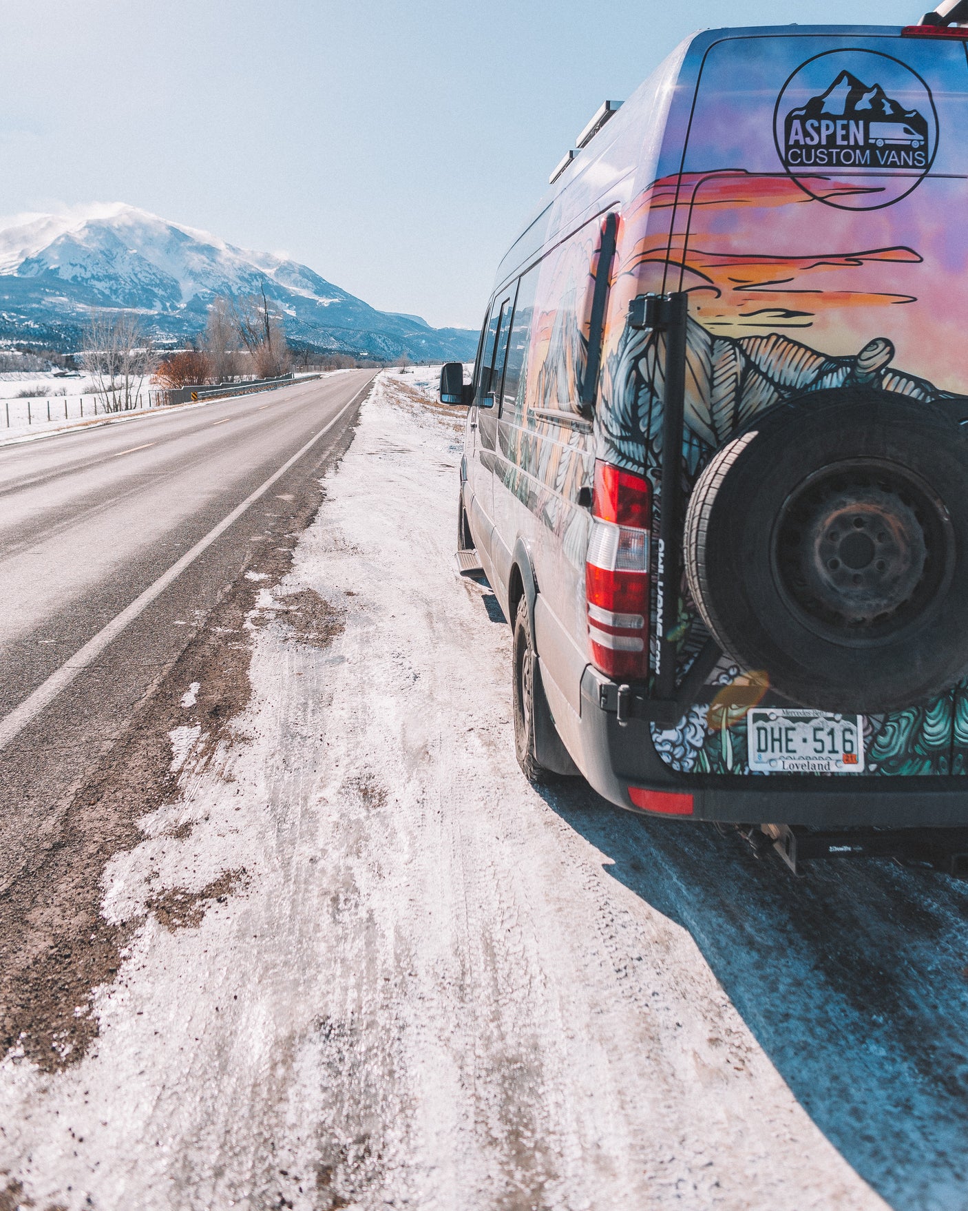 An Aspen Custom Vans camper van, perfect for RV rental adventures, parked on a snowy Colorado mountain road.