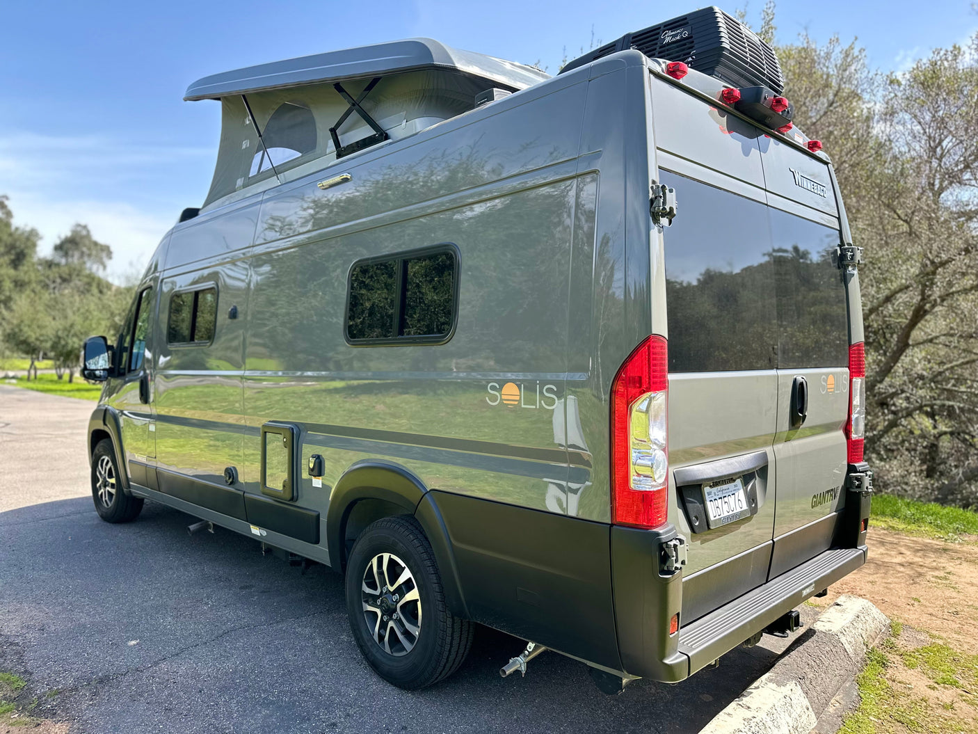 This gray pop-top camper van, a perfect rv rental, is parked outdoors, ready for adventure.