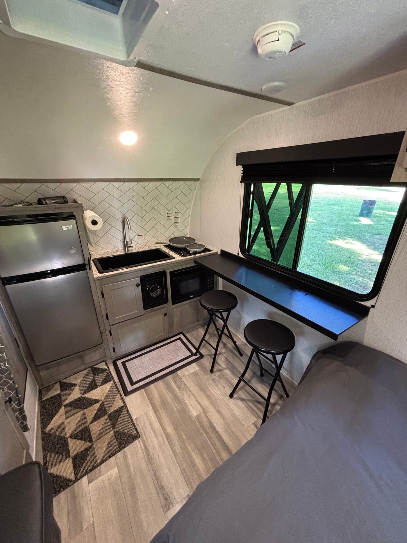 This RV rental's efficient interior boasts a fully equipped kitchenette, cozy dining bar with stools, and a comfortable bed for adventures. — photo 8