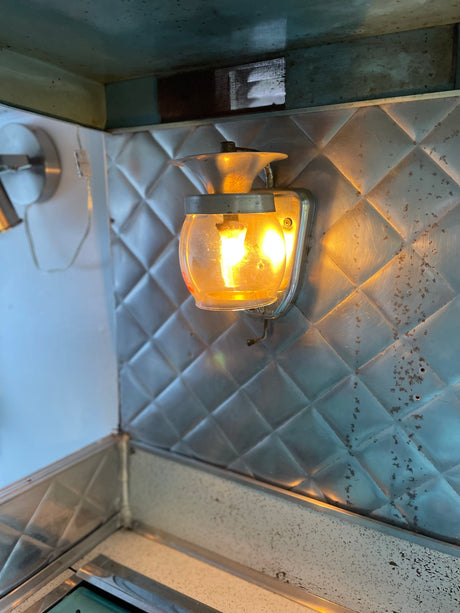 Warm wall light illuminates the diamond-textured metal interior and speckled counter of an rv rental.