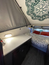 Cozy RV rental interior showcasing a modern bed, functional countertop, and unique ceiling design.