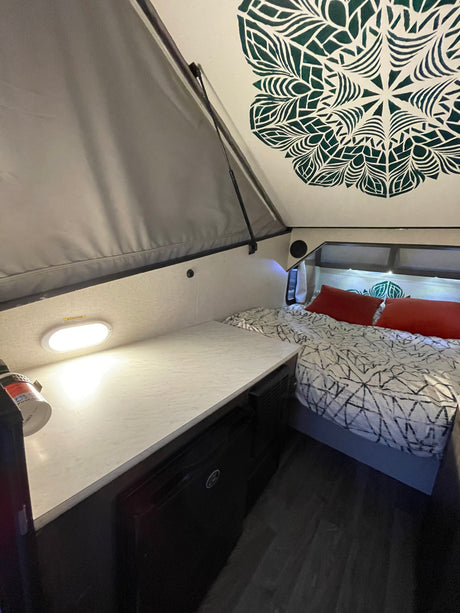 Cozy RV rental interior showcasing a modern bed, functional countertop, and unique ceiling design.