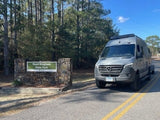 An RV rental parked by the Reed Bingham State Park sign, inviting travelers to outdoor camping adventures.