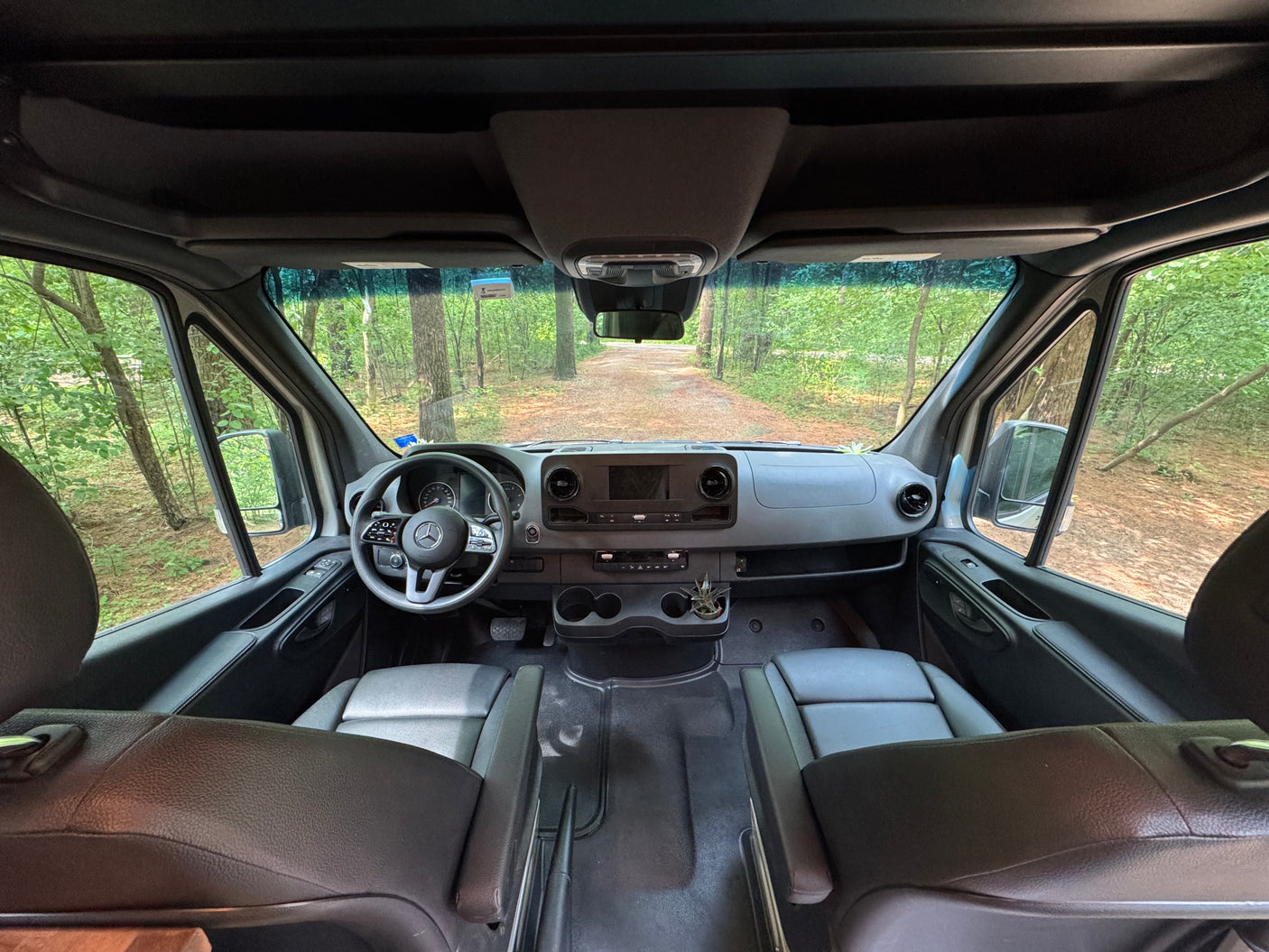 RV rental van interior: dashboard, seats, and forest road view. Ready for your next adventure or road trip.
