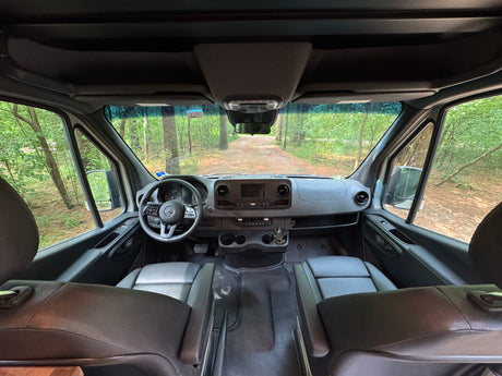 RV rental van interior: dashboard, seats, and forest road view. Ready for your next adventure or road trip.