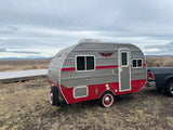 Find your next rv rental: A classic gray & red Retro travel trailer parked with a truck in a wide-open landscape.