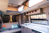 Explore this modern camper van interior, perfect for an rv rental. Features a kitchenette, sofa, and pop-top bed above.