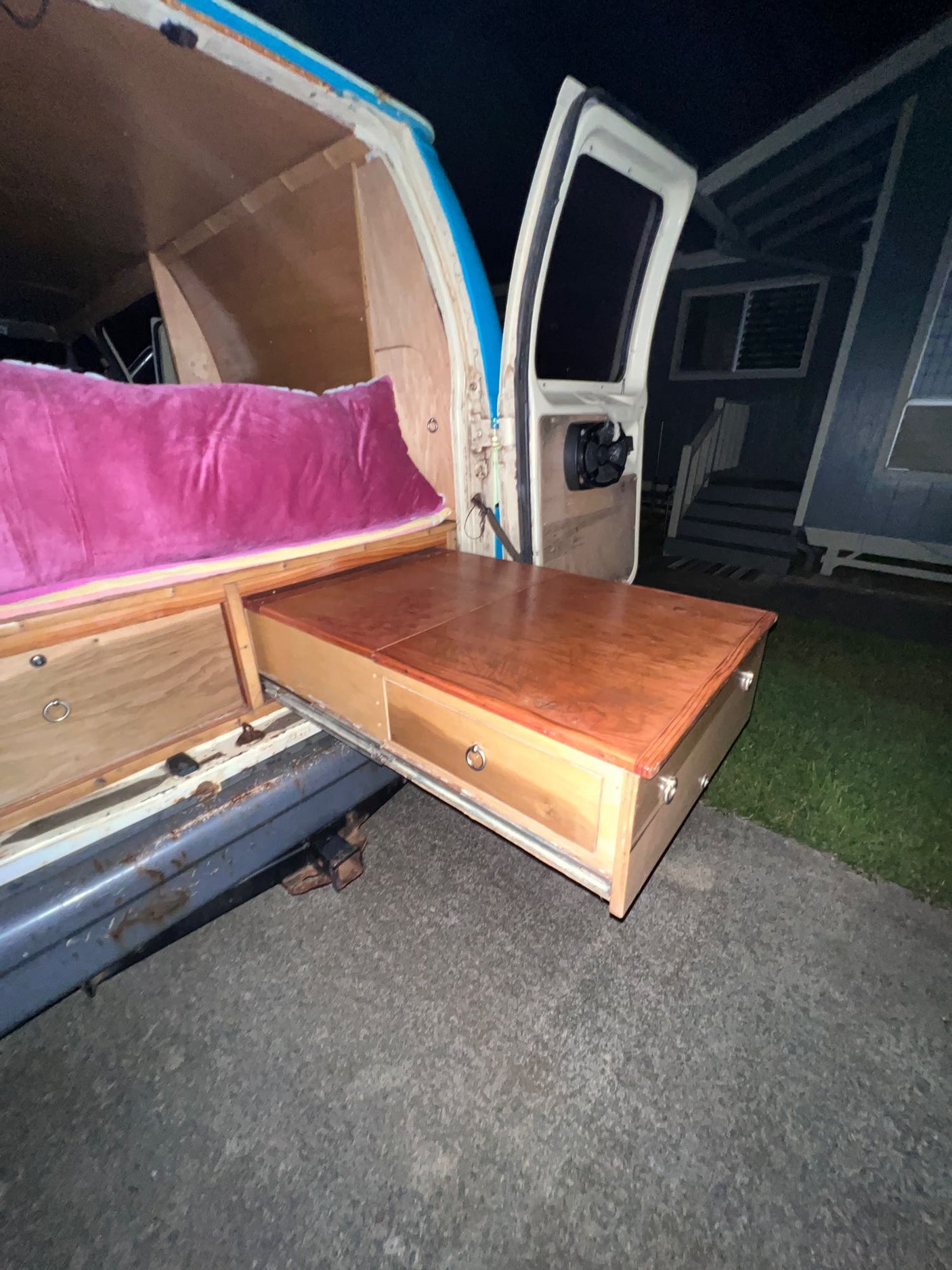 Explore the convenience of an RV rental: a custom camper van with a cozy bed and an extendable outdoor kitchen/table.